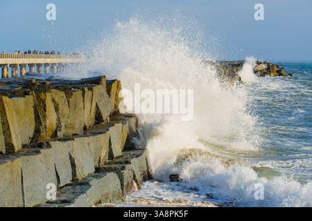 Dynamic waves crash against the rocky jetty near Cabrillo Beach Pier, capturing the energy of the Pacific Ocean and vibrant coastal scenery under clea Stock Photo