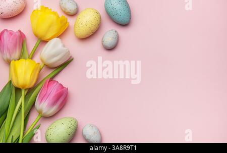 Easter eggs and tulips arranged on a pink background creating a vibrant spring border with copy space Stock Photo