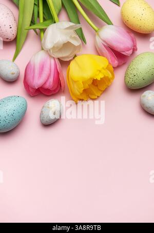 Easter eggs and tulips arranged on a pink background creating a vibrant spring border with copy space Stock Photo