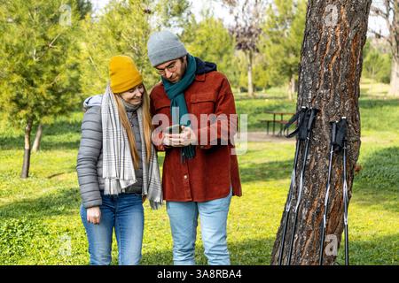 Hikers using smartphone app for checking trekking trail or browsing map during hiking day in the park Stock Photo