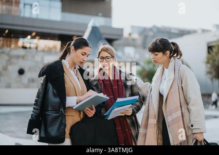 Three businesswomen collaborating on an outdoor meeting with documents Stock Photo