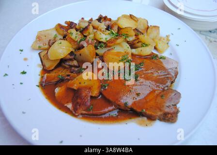Roast pork in beer sauce served with fried potatoes and cabbage salad in Germany Stock Photo