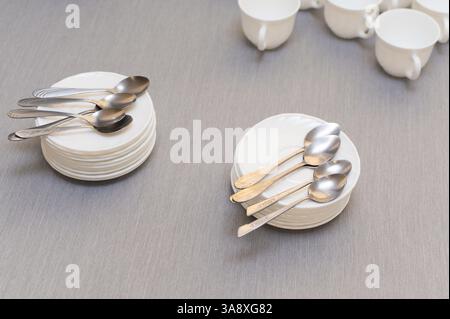 teaspoons on saucers and empty white clean cups on the table Stock Photo