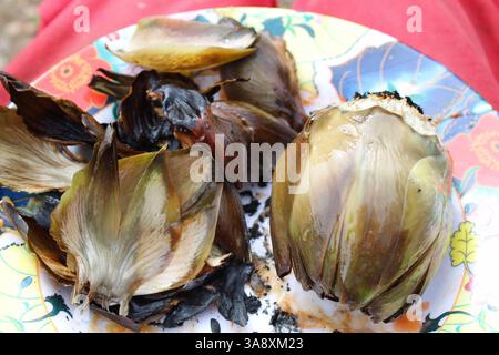 Artichokes which have been cooked over an open fire on a colourful plate Stock Photo