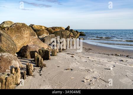 A rocky shoreline with a calm Baltic sea in the background. The water is clear and the rocks are green Stock Photo