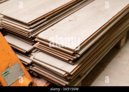 Stack of used laminate flooring planks on a pallet. Reclaimed wood material for renovation, recycling  Stock Photo