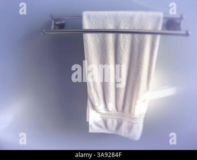 A white bath towel hanging from a towel rack. Stock Photo