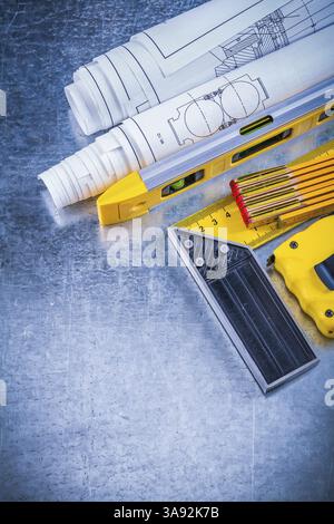 Wooden meter rolls of blueprints square ruler on metallic background ...