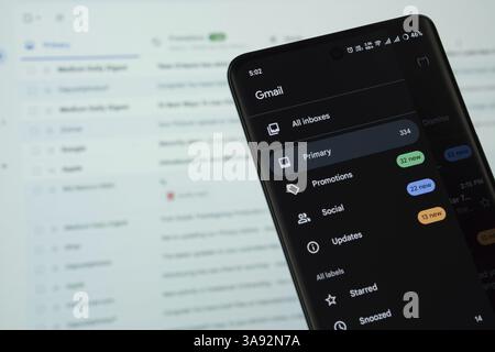 The logo of the Gmail is displayed on a smartphone screen, and the website gmail is visible on a computer screen in the background Stock Photo