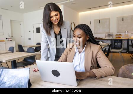 Two businesswomen collaborating on a laptop, enjoying the convenience of working remotely in a hotel lobby during their business trip Stock Photo