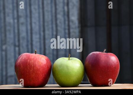 3 or three yellow apples on a clay plate isolated on a wooden background Stock Photo