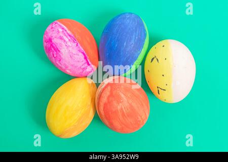 Brightly painted Easter eggs are uniquely arranged on vibrant background, perfect for holiday themes, spring celebrations. Stock Photo