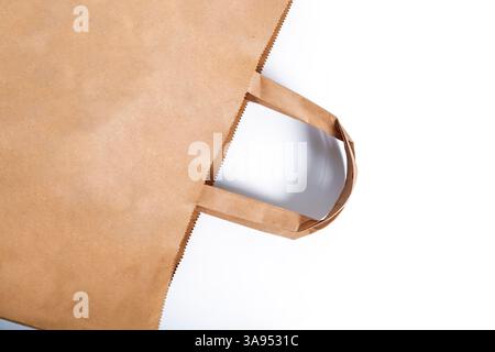 A brown paper bag with sturdy handles placed on a white background. Perfect for packaging, shopping, or environmental presentation. Stock Photo
