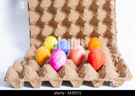 A collection of vibrant hand-painted Easter eggs in a variety of colors housed in an eco-friendly cardboard box. Stock Photo