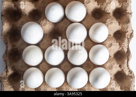 A carton holding twelve white eggs arranged in a grid pattern, viewed from above. Perfect for food, cooking, or egg related concepts. Stock Photo