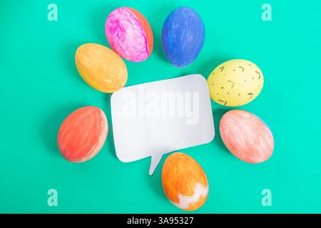 Easter eggs arranged in a circle around a blank speech bubble, set on a bright green background, perfect for seasonal and festive design purposes. Stock Photo