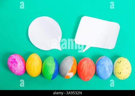 A row of vibrant hand drawn Easter eggs with two empty speech bubbles on a vibrant color background. Perfect for holiday greetings, creative designs, Stock Photo