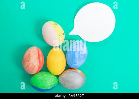 Brightly painted Easter eggs decorated with speech bubbles on a green surface. Perfect for seasonal, holiday, and creative message images. Stock Photo