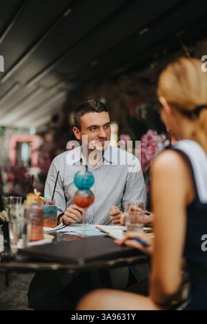 Two people having a friendly conversation over drinks at an outdoor cafe Stock Photo