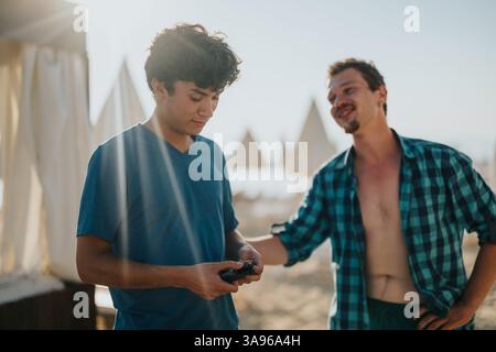 Two friends enjoy a casual moment outdoors at a sunny beach setting Stock Photo