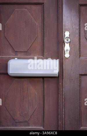 View of a mailbox for newspapers and letters hanging on a wooden door of a house Stock Photo