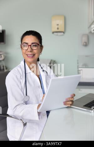 Happy successful mature doctor woman reading patients checkup reports Stock Photo