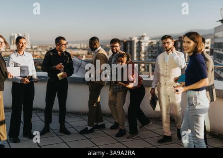 Multicultural team enjoying a sunset break on rooftop balcony Stock Photo