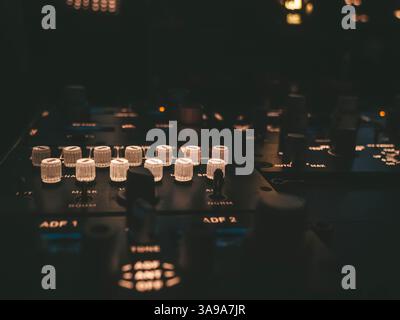 Cockpit controls illuminated in a dimly lit airplane cockpit during flight preparations Stock Photo