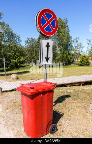a red trash can and a road sign with red circles and blue colors. Stock Photo