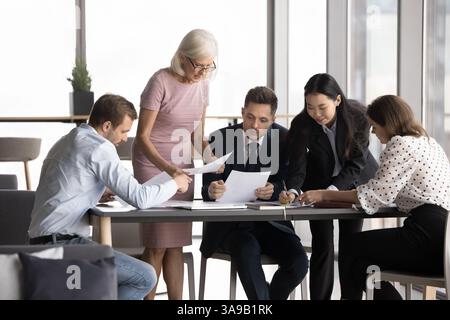 Business people discussing documents gathered around table Stock Photo