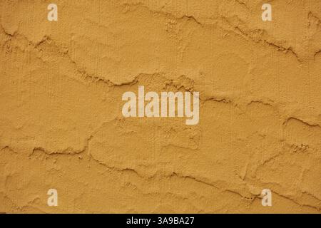 A warm, earthy-toned surface displays a rough, textured pattern with subtle ridges and grooves, reminiscent of natural formations or stucco. Stock Photo