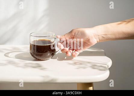 Woman Rests, Her Hand on Mug Filled with Freshly Brewed Coffee, Creating an Inviting and Warm Atmosphere. Stock Photo