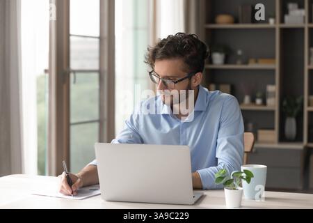 Young man working with notebook taking notes on paper documents Stock Photo