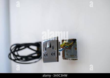 A nickel electrical outlet and Wiring Installation in Progress on White Wall, electrical installation Stock Photo
