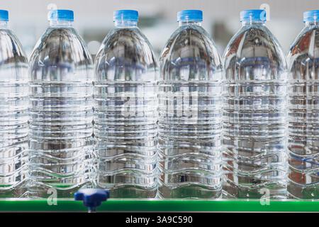 Drinking water production line on conveyor belt. PET Plastic water bottles in drink factory. Pet bottles industry. Stock Photo