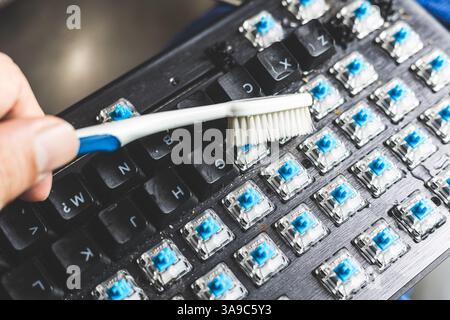Closeup using old tooth brush cleaning dirty dusty computer keyboard Stock Photo