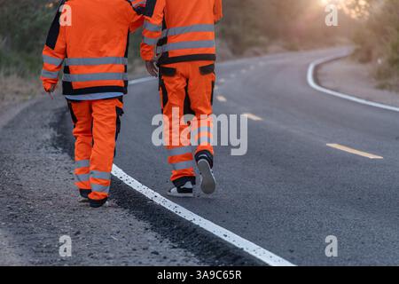 Engineer worker wearing safety suite walking survey inspect at new construction street road highway for final build quality check in sunset Stock Photo