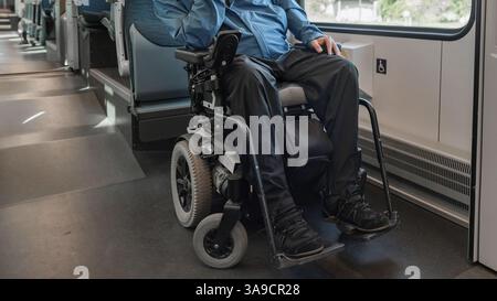 Young wheelchair user traveling by train, watching a landscape through the window. Disability, mobility, and accessibility concepts. Stock Photo