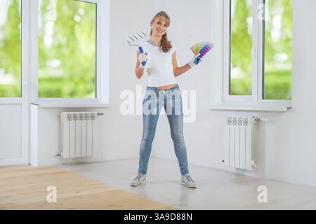 Happy female painter holding paintroller and color palette Stock Photo