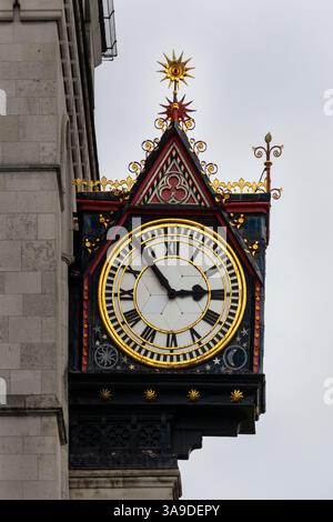Beautiful ornate clock on a stone wall against a grey sky, close up Stock Photo