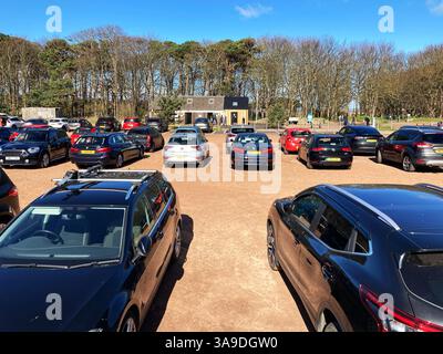 Sunny weather brings out visitors and quickly fills a busy carpark at Yellowcraig beach, Dirleton, East Lothian Scotland Stock Photo