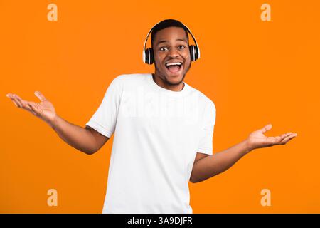 Positive Black Guy In Headphones Listening Music Posing In Studio Stock Photo
