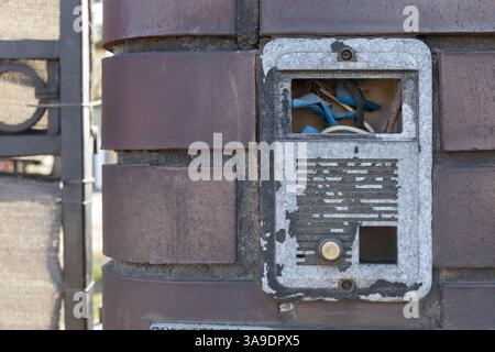 Old Damaged Intercom with Exposed Wires on Brick Wall Stock Photo