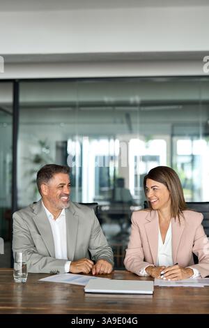 Two executive managers working and taking at meeting in office. Vertical Stock Photo