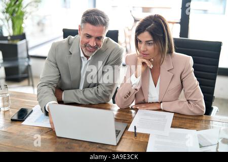 Busy professional business managers working in office looking at laptop. Stock Photo