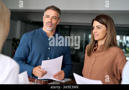 Busy mature executive manager discussing documents with business team. Stock Photo