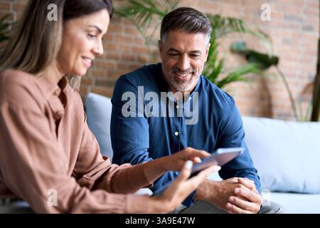 Happy mature female executive manager holding digital tablet consulting client. Stock Photo