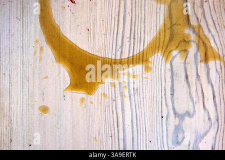 Abstract splash of spilled liquid coffee or sauce on a light wooden surface, creating an organic, irregular pattern. Copy space Stock Photo
