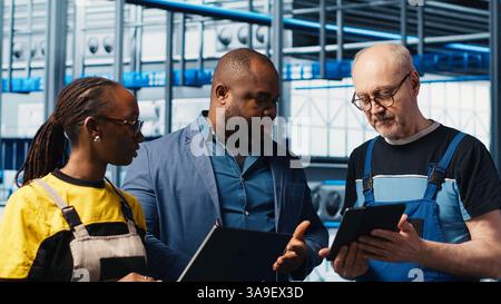 Supervisor overseeing work done by engineers in industry 4.0 solar panels plant to reduce downtime. Photovoltaics smart factory manager tasking workers with fixing damaged IoT sensors, camera A Stock Photo