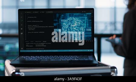 Focus on laptop used by teamworking data center computer scientists in background using artificial intelligence. Notebook screen with neural networks doing computing processes, camera A close up Stock Photo
